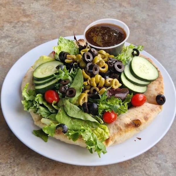 Angelo's West Italian salad with lettuce, olives, cucumbers, tomatoes, and dressing on a pita.